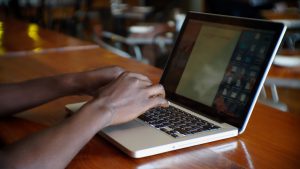 african stock video of a black african man sitting at a restaurant typing on his laptop computer 3